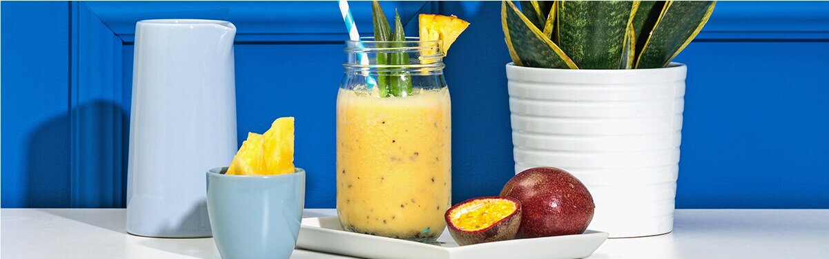 Ananas Passionsfrucht Smoothie mit einer Passionsfrucht und Ananas daneben
