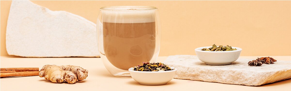 Chai Tea Latte mit Gewürzen daneben