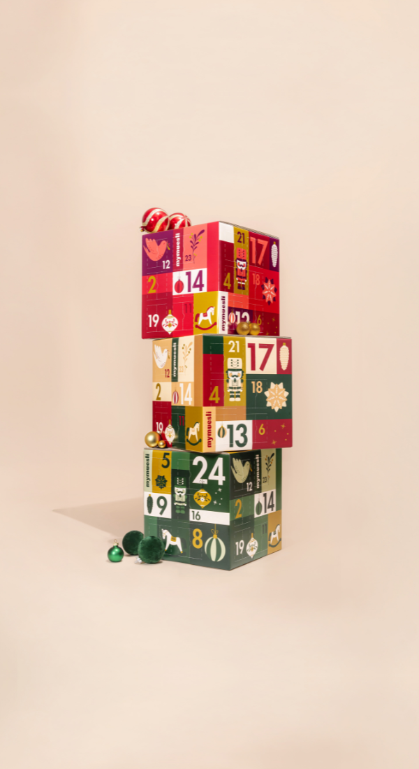 mymuesli bio Adventskalender gestapelt vor einem beigen Hintergrund in den Sorten Müsli, Porrdige und Müsli und Porridge