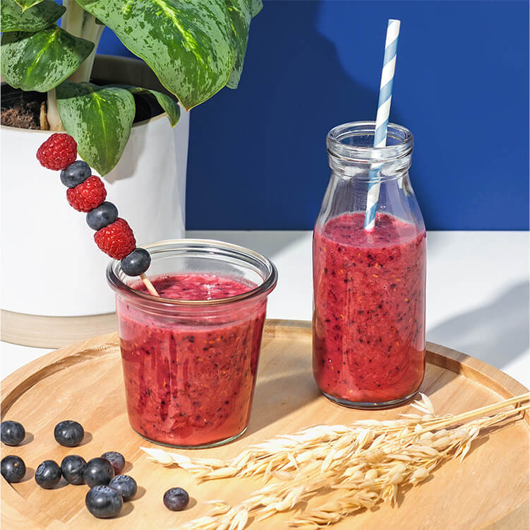 Frühstücksdrink mit Beeren und Hafer daneben