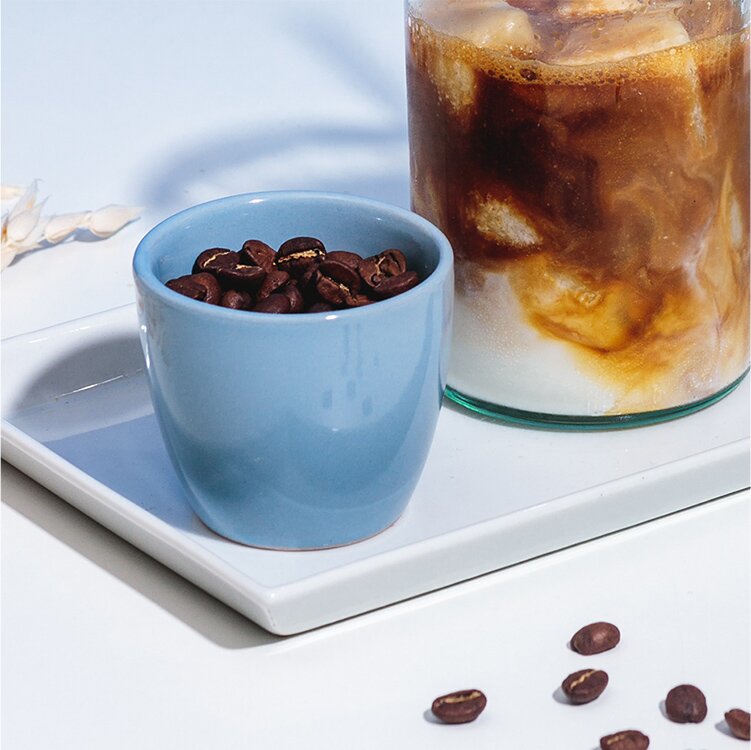 Eine Tasse Kaffeebohnen und Eiskaffee daneben