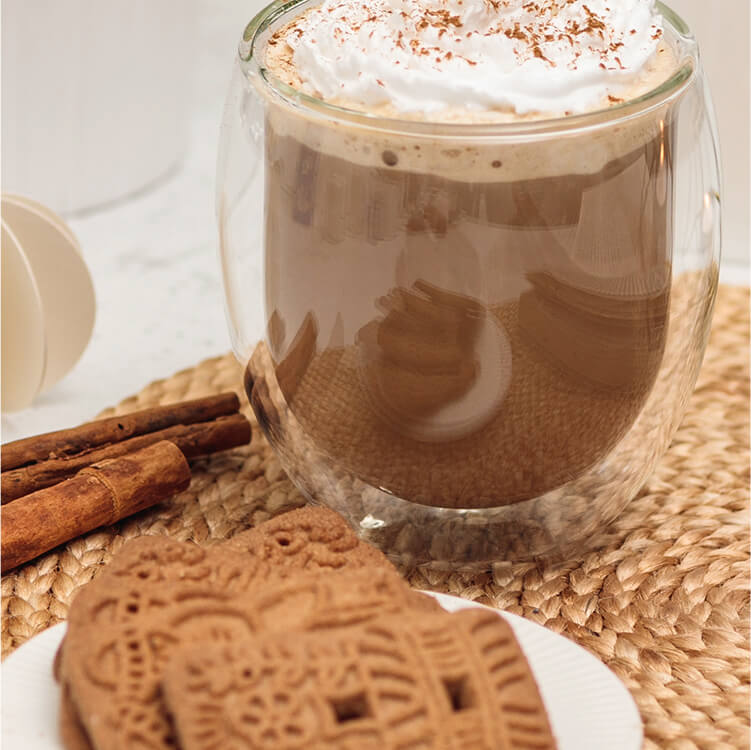 Gingerbread Latte mit einem Teelicht, Spekulatius Keksen und Zimtstangen daneben