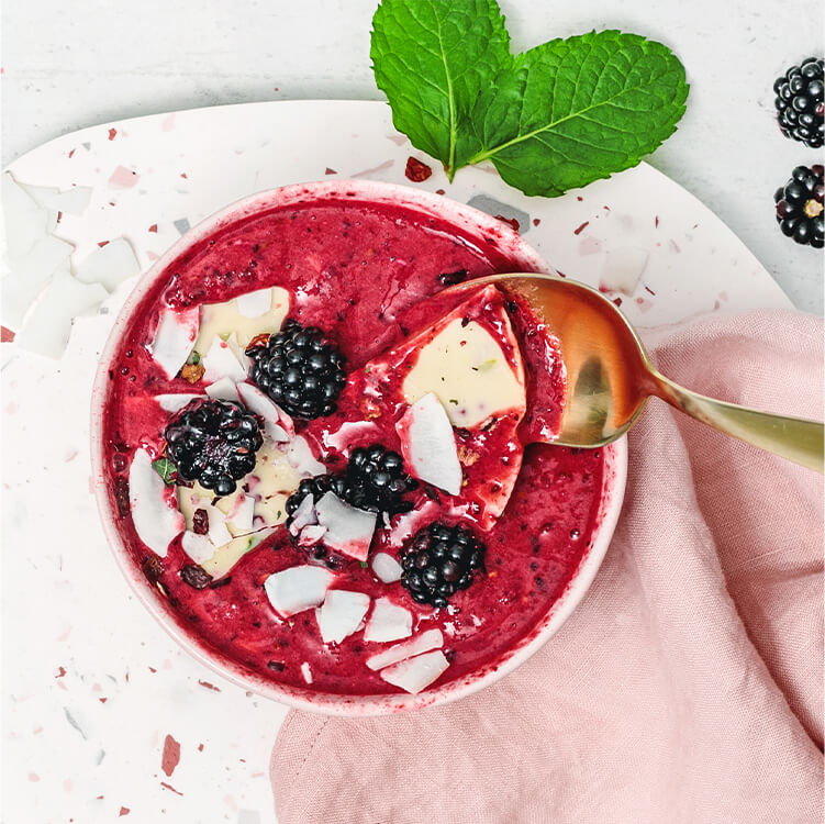 Magic Shell Smoothie Bowl mit Beeren und Kokoschips dekoriert