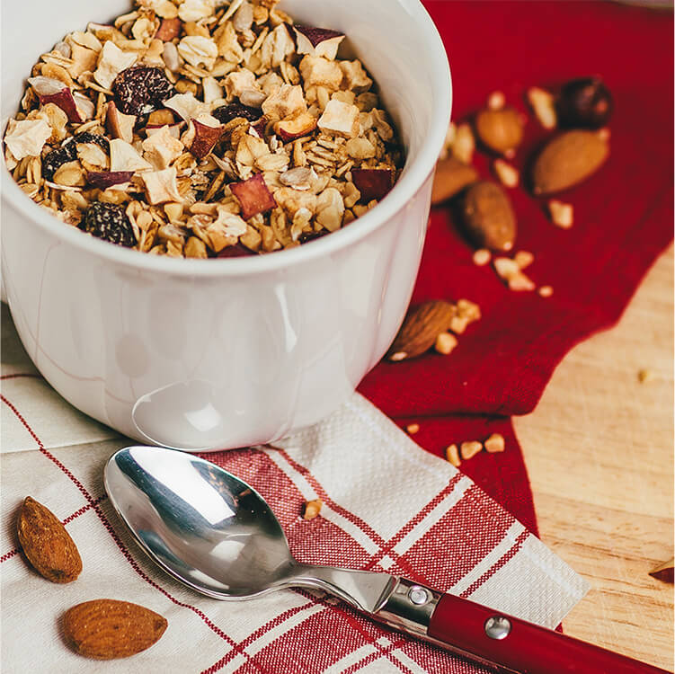 Müsli in einer Tasse mit einem Löffel daneben