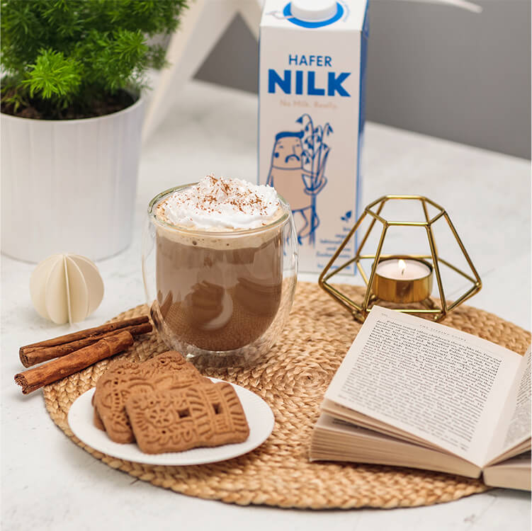 Gingerbread Latte mit einem Teelicht, Spekulatius Keksen und Zimtstangen daneben