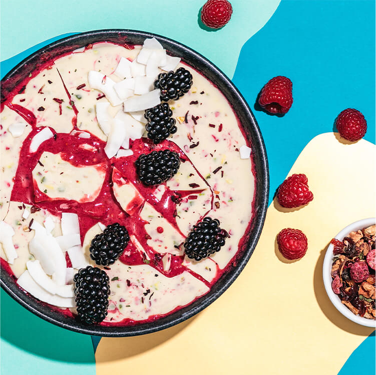 Magic Shell Smoothie Bowl mit Beeren und Kokoschips dekoriert