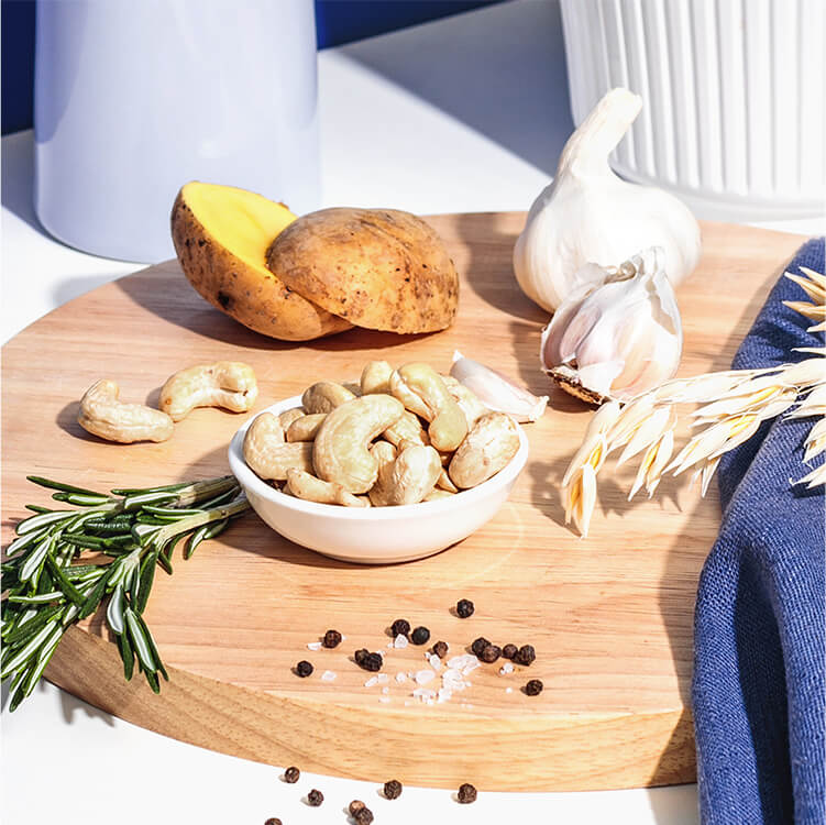 Kartoffeln, Knoblauch, Rosmrin und Cashewkerne auf einem runden Holzbrett