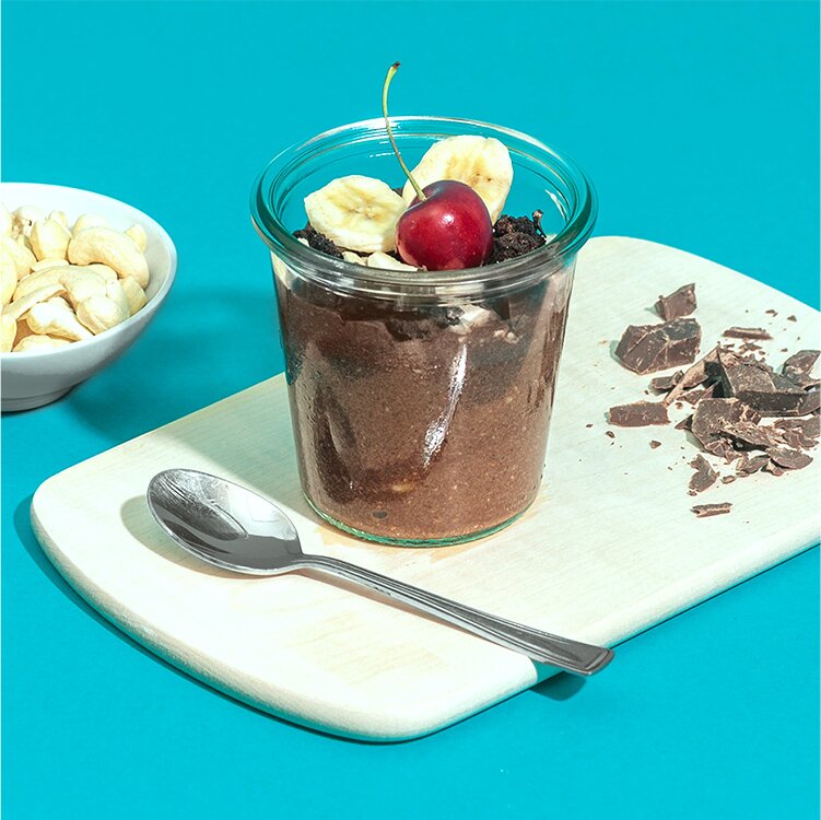 Schoko Bananen Nicecream mit einer Kirsche und Banane dekoriert