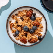 mymuesli Bio Blueberry Cassis Granola in Schale mit Joghurt und frischen Blaubeeren