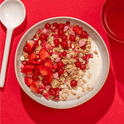 mymuesli Bio Low Sugar Berry Crunch in Schale mit Joghurt, frischen Johannisbeeren und Erdbeeren
