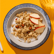 mymuesli Bio Low Sugar Roasted Nuts Müsli in Schale mit Joghurt und frischen Äpfeln