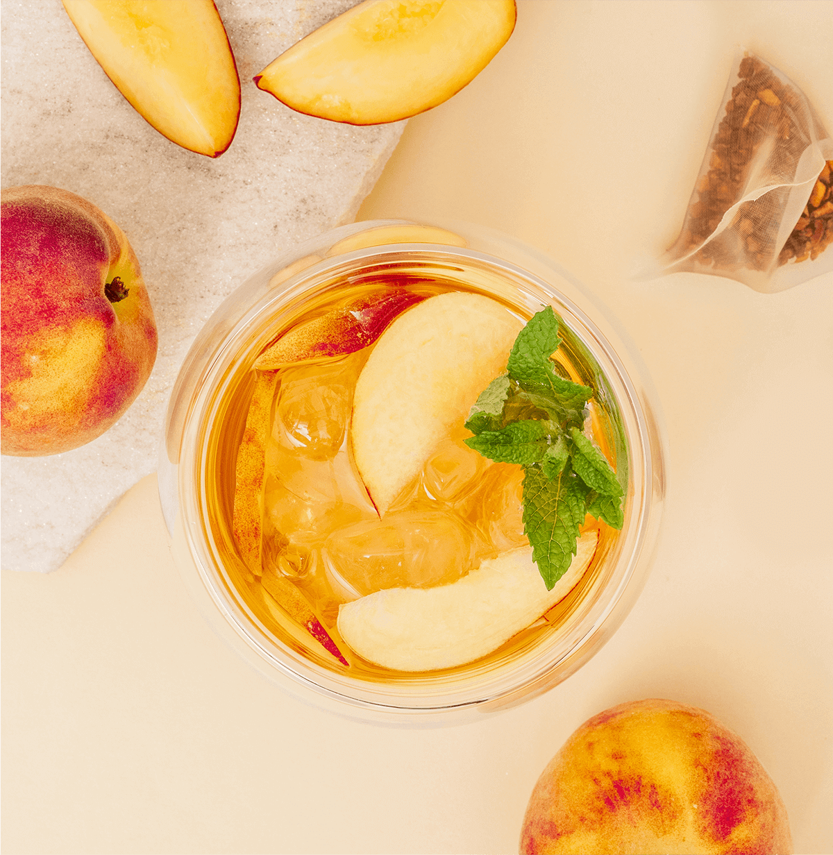 Tree of Tea Ice Tea Peach im Glas mit Pfirsichen daneben
