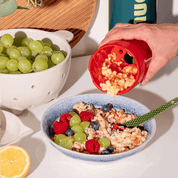 Geriebener Apfel wird von der Apfelreibe auf Bircher gefüllt