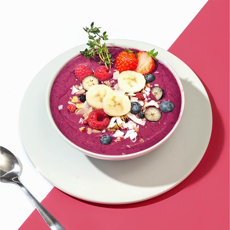 Acai Smoothie Bowl mit Bananenscheiben und Beeren dekoriert