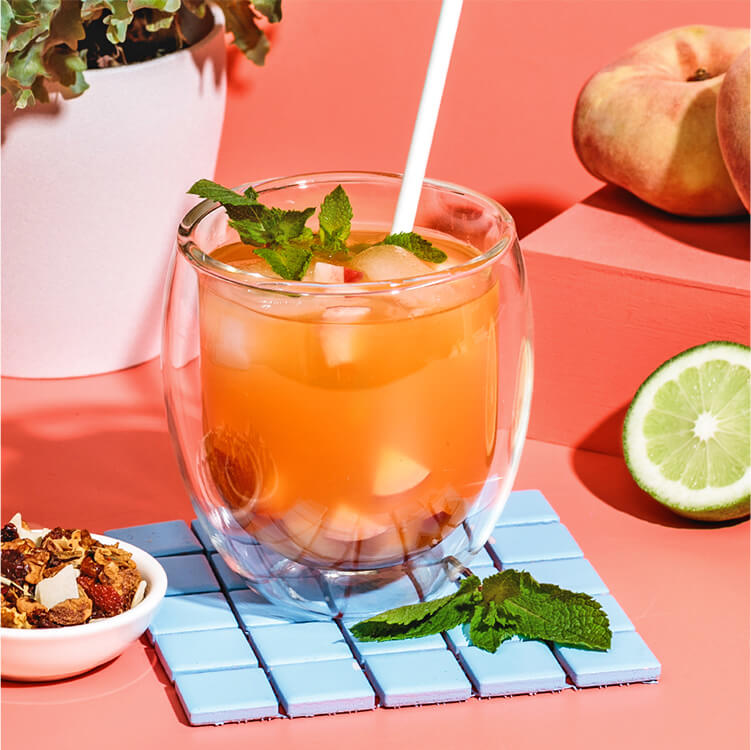 Peach Drink in einem Glas mit Tee und einer halben Limette daneben