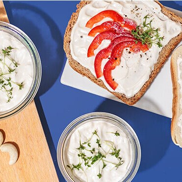Cashew Frischkäse Sandwiches auf einem Teller mit Cashews daneben