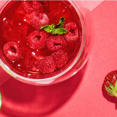 Minty Ruby in einem Glas mit Himbeeren und einer halben Limetten