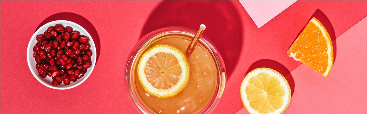 Roi Sour Cocktail mit Granatapfelkernen und Zitrone daneben