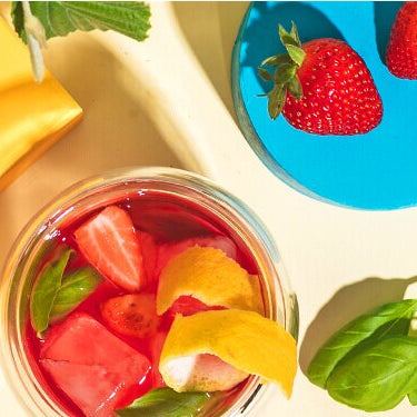 Strawberry Basil Smash im Glas und daneben Erdbeeren und eine halbe Zitrone