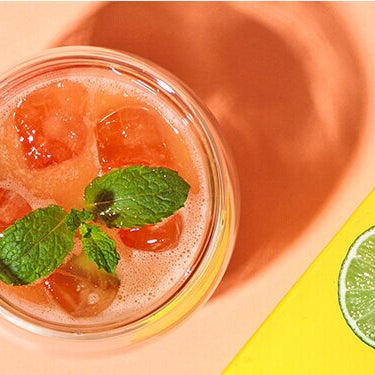 Papaya Eistee mit einer halben Papaya, Limette und Tee daneben