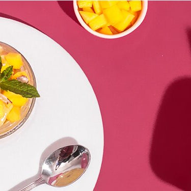 Mango Nicecream in einem Glas mit Mango und Nüssen dekoriert