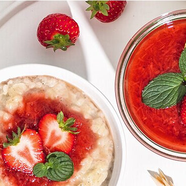 Milchreis mit Rhabarber-Erdbeer-Kompott im Glas und mit einer Zitronenscheibe und ganzen Erdbeeren dekoriert