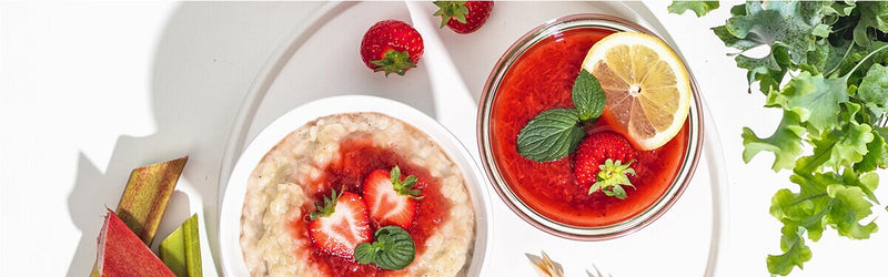 Milchreis mit Rhabarber-Erdbeer-Kompott im Glas und mit einer Zitronenscheibe und ganzen Erdbeeren dekoriert