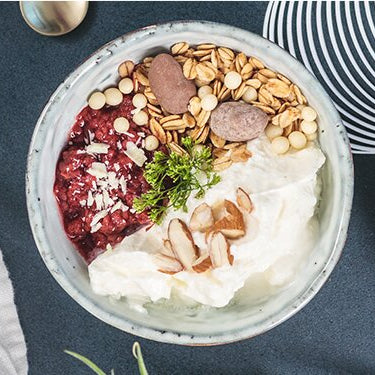 Winterliches Quark-Himbeerkompott mit Adventsmüsli auf einem Teller