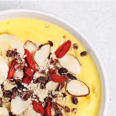 Mango-Kurkuma Bowl in einer Schale mit Bananenscheiben