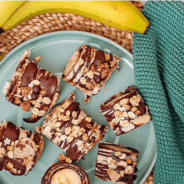 Schoko Bananen Sushi auf einem Teller mit Banane daneben