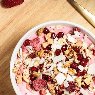 Breakfast Smoothie Bowl auf einem Tablett mit einem Kaffee und goldenen Löffel daneben