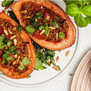 Tomate-Brokkoli-Süßkartoffel auf einem Teller, daneben Schüsseln mit Cashews, Tomaten und Lauchzwiebeln