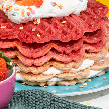 Waffeltorte auf einem Teller mit Erdbeeren daneben