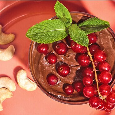 Mousse au Chocolat in einem Glas mit Cashews und Johannisbeeren dekoriert