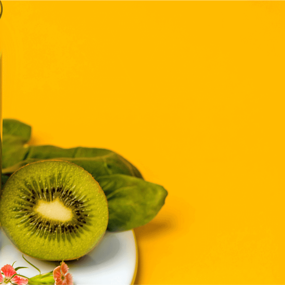 Green Smoothie in einem Glas mit einer halben Kiwi daneben