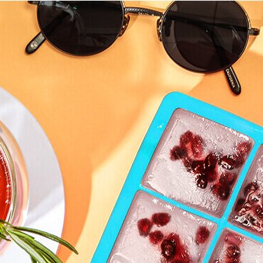 Grapefruit Granatapfel Eistee in einem Glas und daneben ein Eiswürfelförmchen