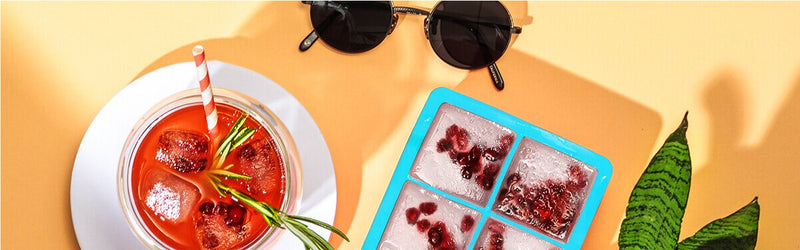 Grapefruit Granatapfel Eistee in einem Glas und daneben ein Eiswürfelförmchen