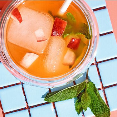 Peach Drink in einem Glas mit Tee und einer halben Limette daneben