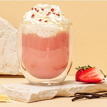 Pink Hot Chocolate mit Sahne und Erdbeeren daneben