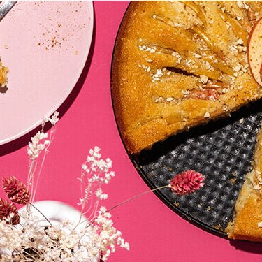 Apfelkuchen in einer Springform und daneben ein Teller mit einem Kuchenstück