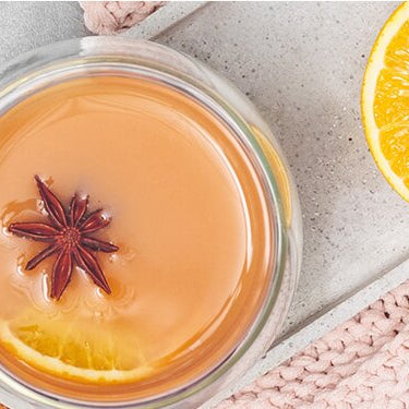 Glory's Chai Punsch in einem Glas mit Gewürzen und einer halben Orange