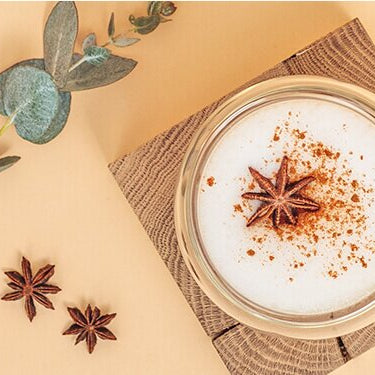 Chai Tee Latte mit Tee und Gewürzen daneben