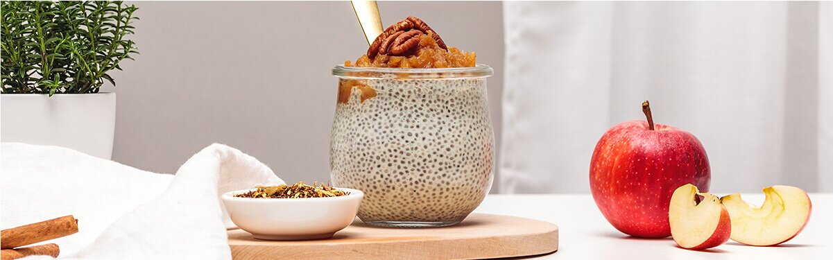 Chiapudding mit Nüssen dekoriert und daneben ein Apfel