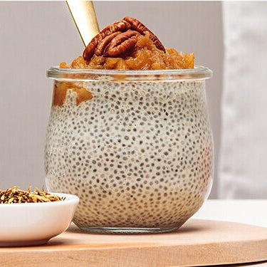 Chiapudding mit Nüssen dekoriert und daneben ein Apfel