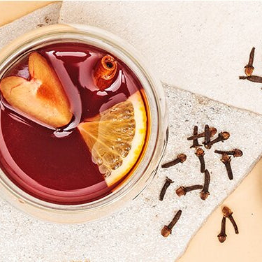 Pflaumen Punsch mit Orangen, Nelken und Tee daneben