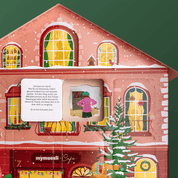 Nahaufnahme des rotes Adventskalenderhaus. Die Fenster des Hauses sind beleuchtet. Ein Türchen ist geöffnet und zeigt die Innenseite des Kalenders. In der Tür steht ein Teil der Weihnachtsgeschichte. Diese ist als Bild auf der Rückwand des Hauses.