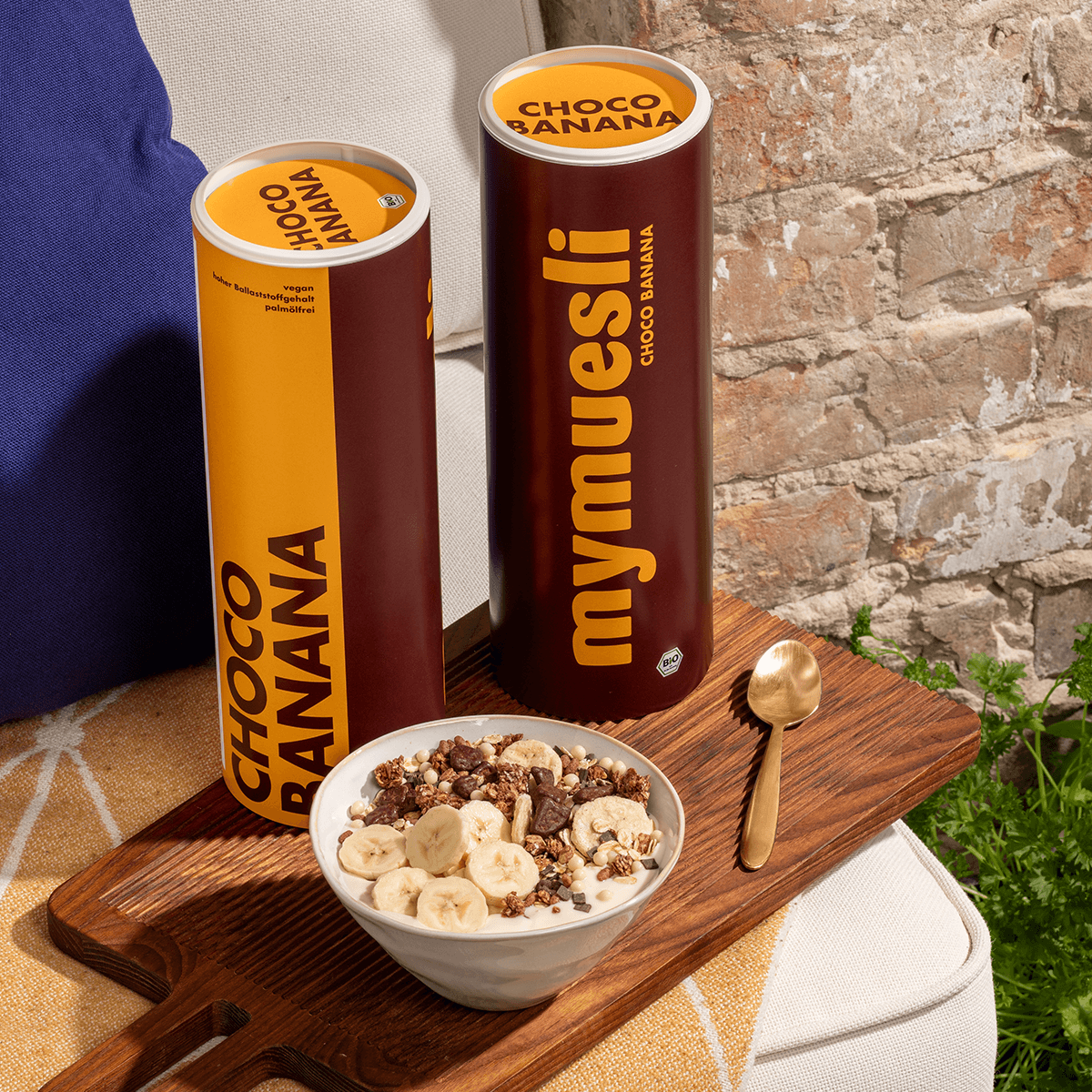 mymuesli Bio Choco Banana Müsli zubereitet neben Choco Banana Müsli Dosen