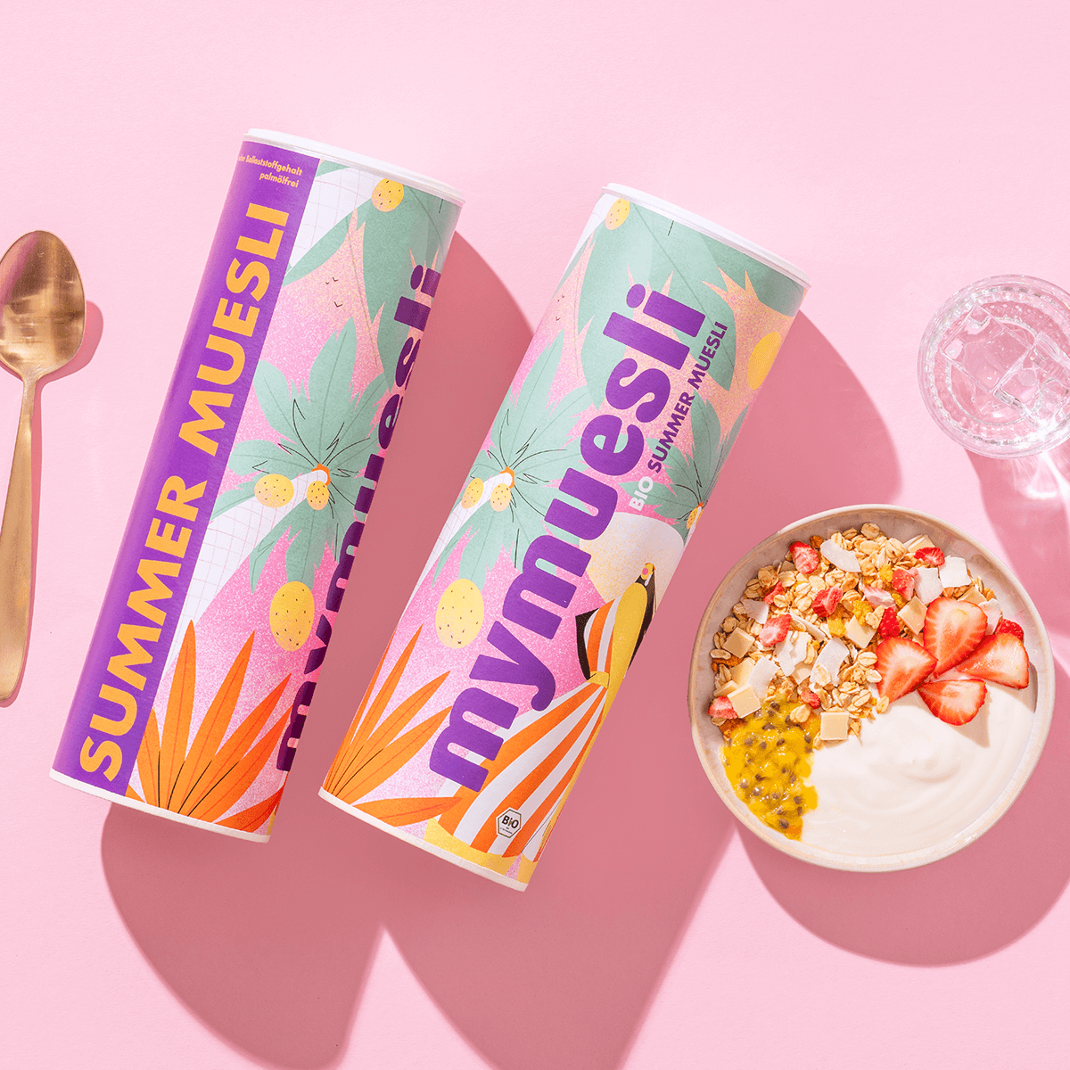 mymuesli Bio Sommer Müsli in Schale mit frischen Früchten neben Dosen