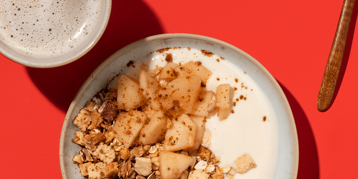 mymuesli Bio Apple Crumble Müsli serviert mit warmen Apfelstücken, Zimt und Joghurt
