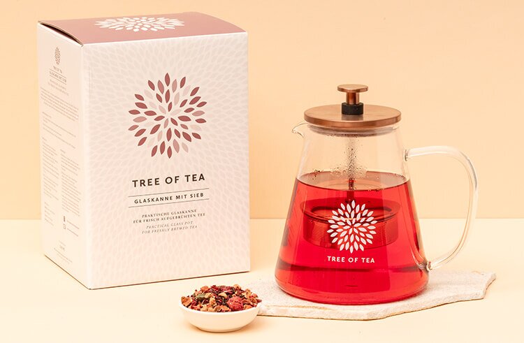 Glaskanne mit Sieb Tree of Tea neben der Verpackung